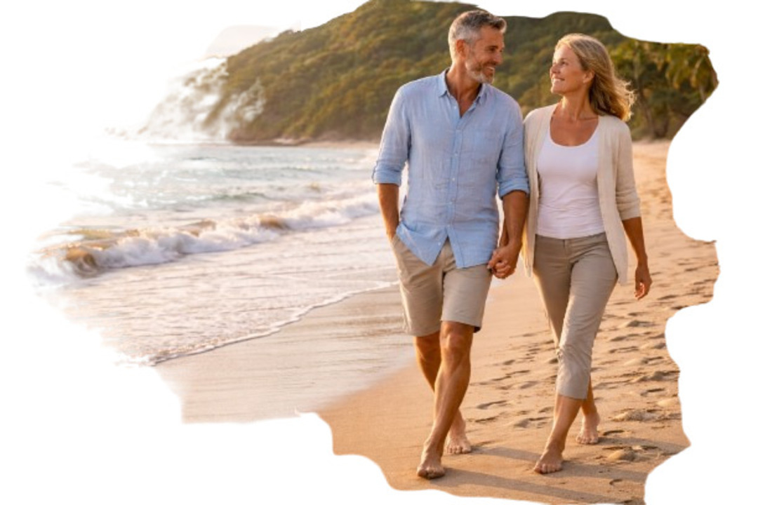 Pareja de adultos caminando juntos en la playa al atardecer, reflejando tranquilidad, bienestar y retiro sin preocupaciones.